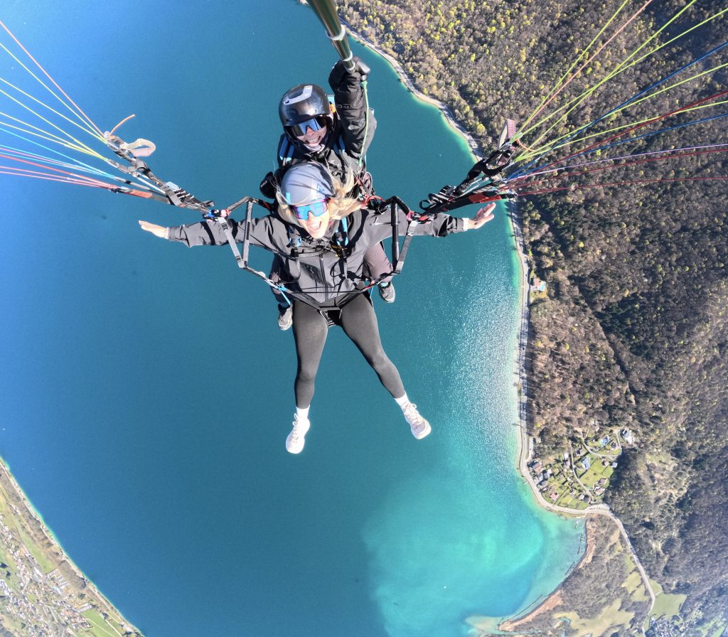 Vol tandem en parapente avec un passager souriant au-dessus du lac d'Annecy